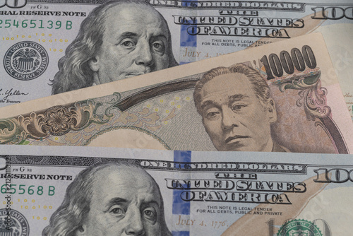 Japanese 10000 yen banknote placed between US 100 dollar bills