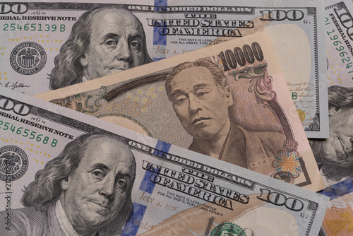 Japanese 10000 yen banknote placed between US 100 dollar bills