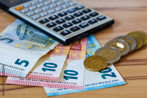 Euro banknotes, coins and calculator on wooden table for personal finance, budgeting and accounting