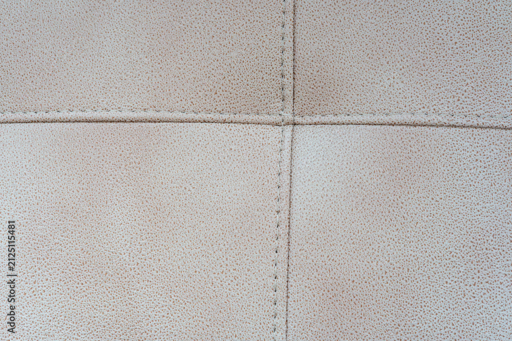 Naklejka premium Close-up of a beige tufted leather upholstery texture with stitched crossed seams