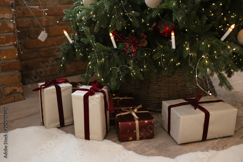 Christmas presents in a box with a red ribbon lie under the Christmas tree