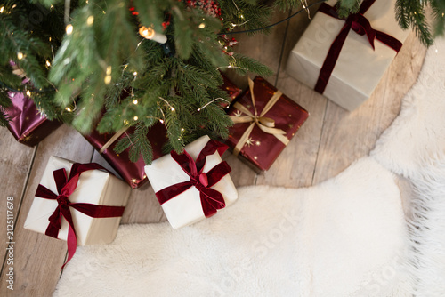Christmas presents in a box with a red ribbon lie under the Christmas tree