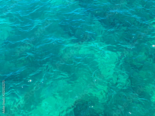 Фотография Clear turquoise sea water with gentle waves and sunlight reflections