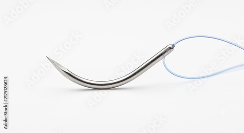 Extreme macro of a surgical suture needle tip. Tiny curved stainless steel needle bonded to a translucent blue monofilament thread. Isolated on pure white.