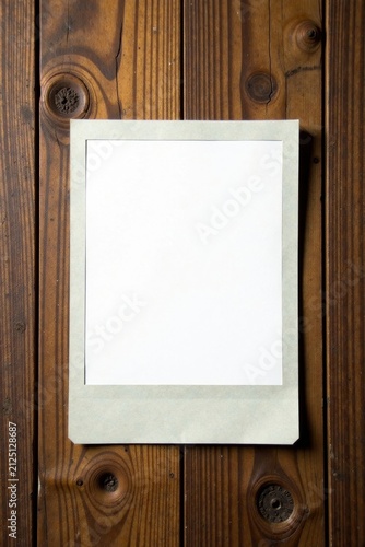 Blank instant photograph frame against rustic wooden background, perfect for adding your own design or image.