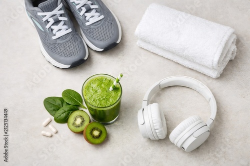 Fitness accessories, a refreshing green smoothie with fresh kiwi and spinach, and health supplements arranged on a light background, representing wellness and an active lifestyle