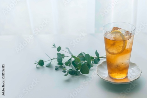 Refreshing iced lemon tea with eucalyptus on a white table and copy space