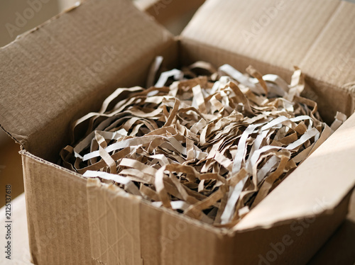 Top down view into open cardboard box filled with shredded paper filler