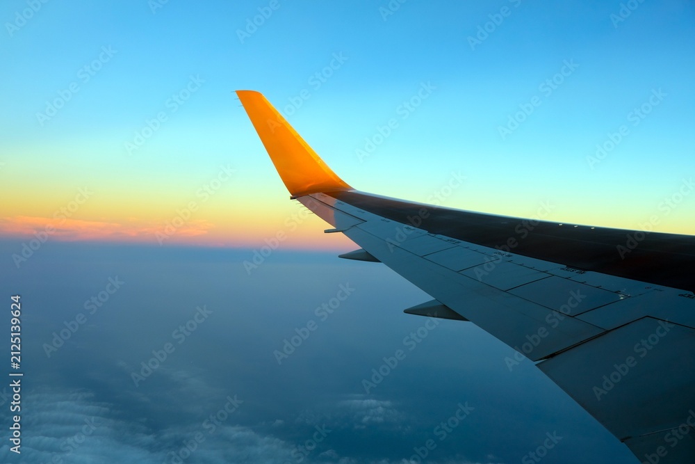 Fototapeta premium 飛行機の窓から見る上空の夕焼けと主翼