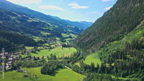Village in green alpine valley surrounded by forested mountains