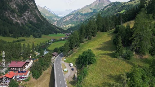 Aerial view of mountain road through green valley and village