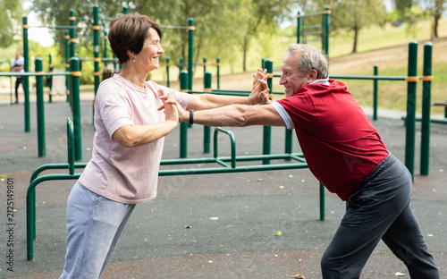 Konstfotografi elderly man and woman do gymnastics on an outdoor sports ground
