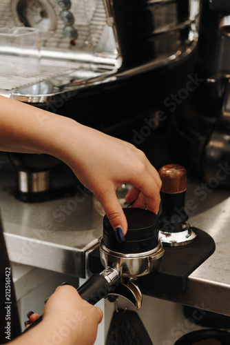 Bild auf Leinwand Barista compressing freshly ground coffee with a tamper before brewing espresso