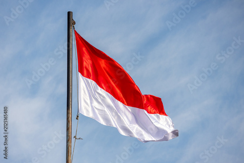 The red and white Indonesian flag waves proudly against a clear blue sky