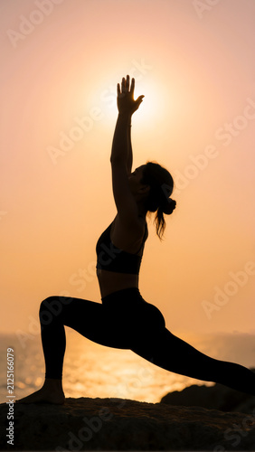 Silhouette donna che fa yoga al tramonto sulla scogliera