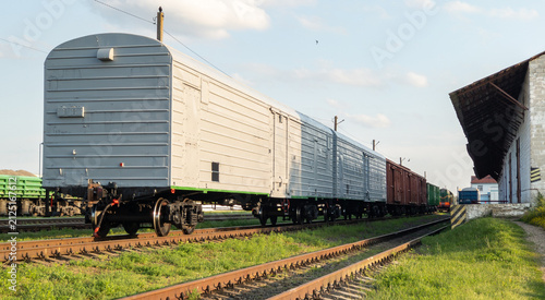 Konstfotografi Grey Freight Train Railway Cars Standing on Tracks Near Industrial Warehouse Pla