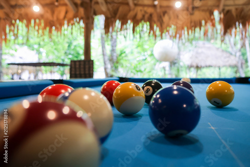 Fotografía Billiard balls scattered on blue pool table under thatched roof in tropical leis