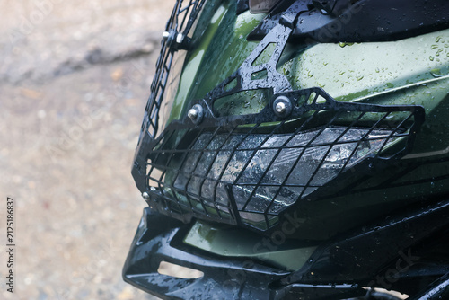Konstfotografi Green offroad vehicle front end with protective metal grille and wet headlight a