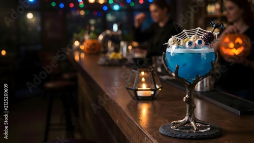 Halloween cocktail on a bar counter. Spooky blue drink with eyeballs and spider web decor.