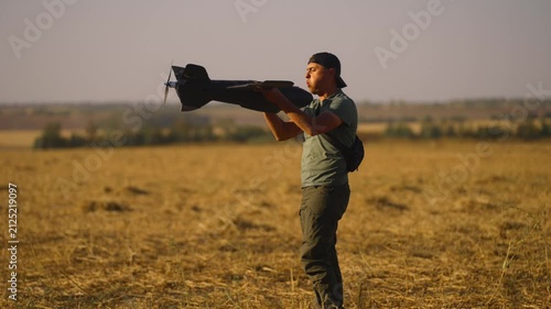 man UAV pilot with plane drone in hands preparing to launch drone in field at summer evening. preflight check. technology and engineering in modern warfare.