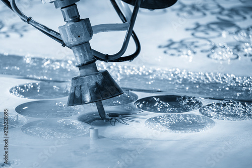 Multi axis abrasive waterjet cutting machine cutting aluminum plate in light blue lighting
