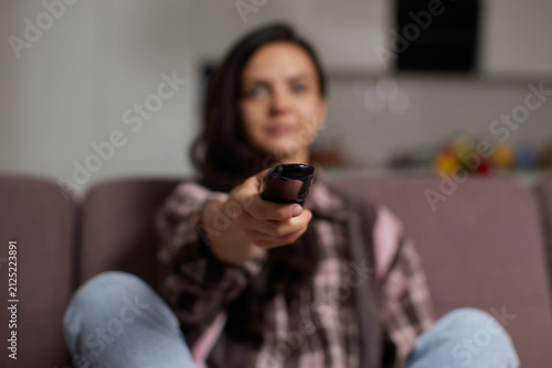 Cuadro en lienzo Woman changing tv channel with remote control