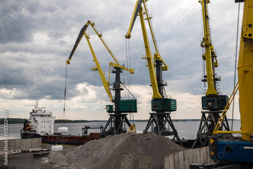 Massive harbor cranes in seaport. Heavy load dockside cranes in port, cargo container yard, container ship terminal. Business and commerce, logistics. 