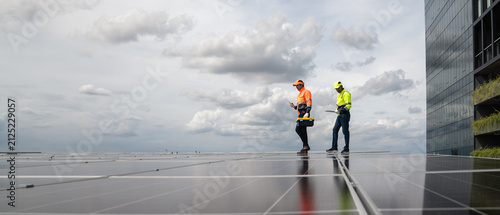 Solar Technicians Survey a Large Rooftop Photovoltaic Array While Reviewing Renewable Energy System Performance at a Commercial Building for Maintenance Planning