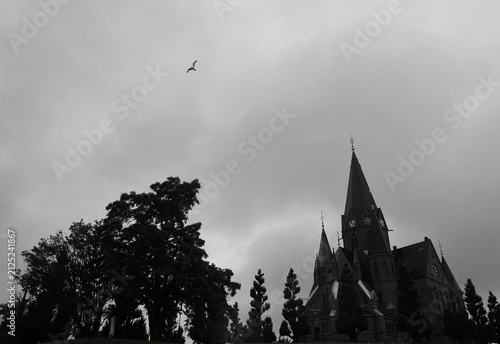 Silhouette of a church and trees under a cloudy sky