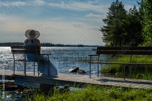 Woman sitting on a dock in  summer evening