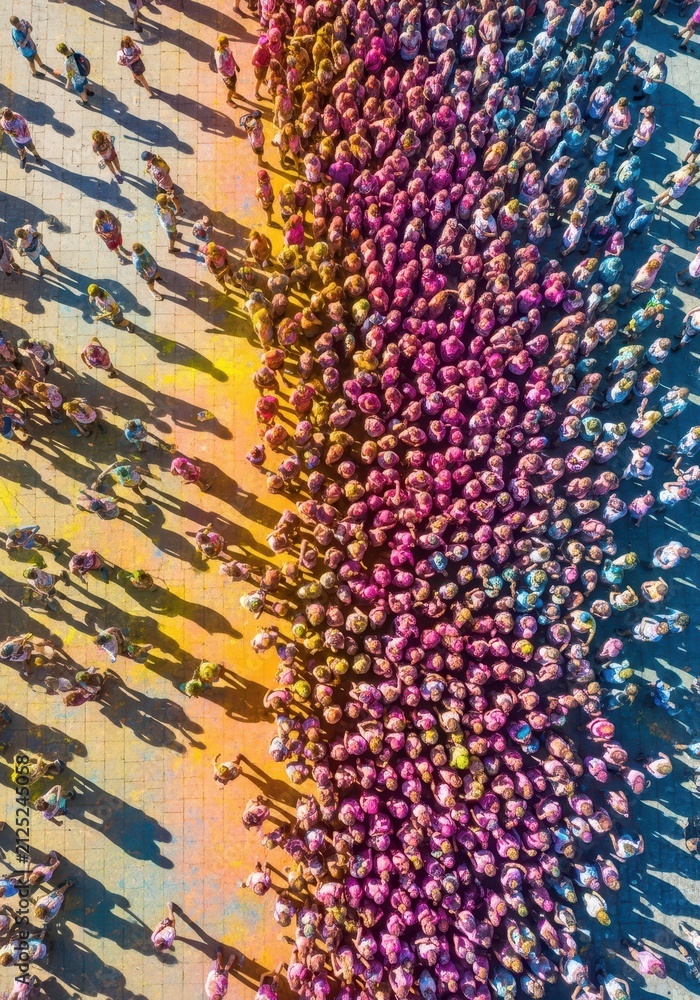 Fototapeta premium Aerial View of a Large Crowd Celebrating Holi Festival with Vibrant Colors and Long Shadows on Pavement