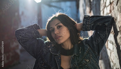 Young woman with hands behind head in denim jacket