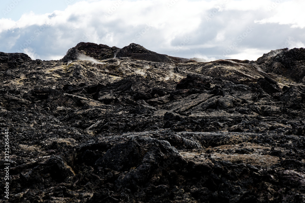 Obraz premium Steaming Lava Field Under Cloudy Sky
