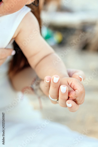 Tender Close Up of Mother's Hand Holding One Year Old Daughter's Hand
