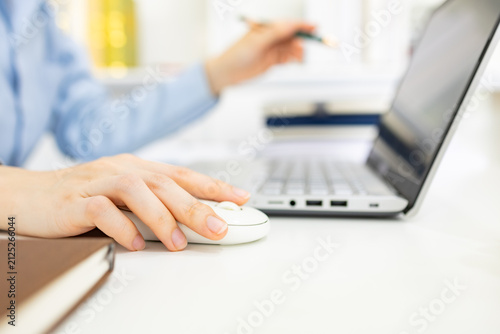 Woman analyzes charts on a laptop. She studies data with focused intent. Desk holds plants, notes, and a phone. Professional workspace with soft lighting

