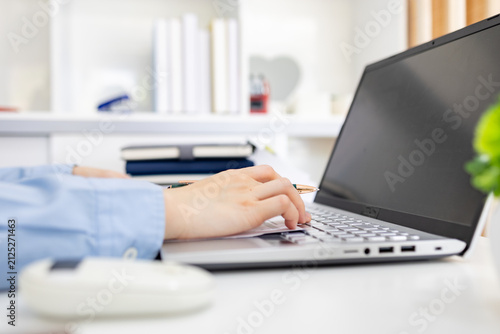 Woman analyzes charts on a laptop. She studies data with focused intent. Desk holds plants, notes, and a phone. Professional workspace with soft lighting
