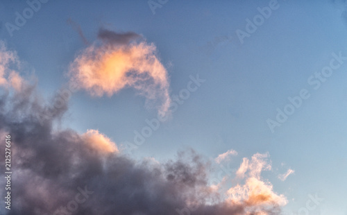 Cloudscape with white fluffy clouds in sunset sky