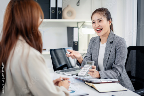 Businesswoman explains financial data with calculator to client colleague in modern office setting for successful planning strategy