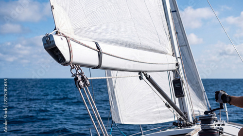 Sailboat boom and rigging with hand on winch at sea