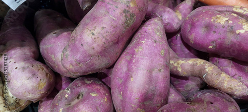Purple sweet potatoes on a market stall. Close-up.
