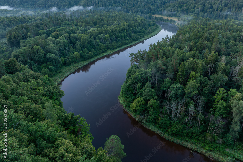 Obraz premium Aerial view of the winding Gauja River at misty sunrise in Gauja National Park, Sigulda, Latvia