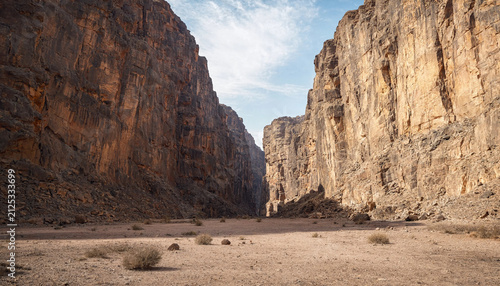 Narrow canyon passage with towering vertical limestone cliffs in arid desert landscape mountain wilderness adventure geological formation outdoors canyonlands exploration