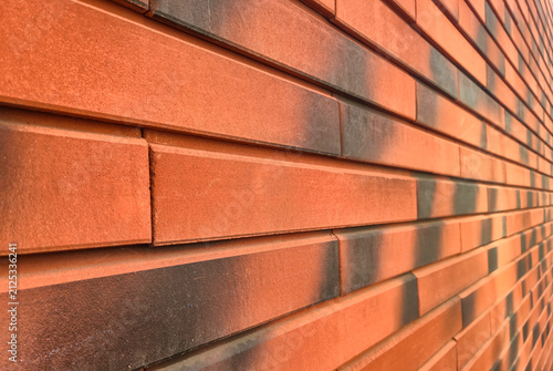 Quadro su tela Close-up of the texture of a modern orange brick wall with black soot