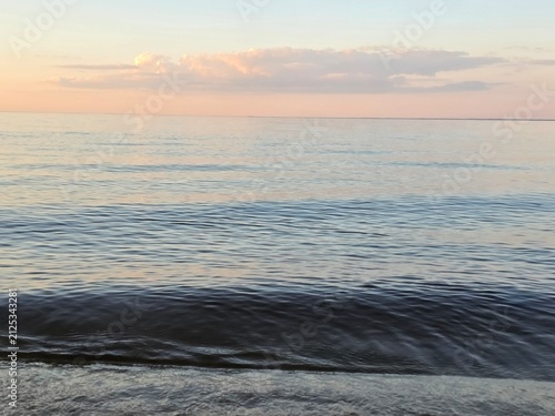Bild auf Leinwand Calm Waves Dance Under a Pastel Sky at Dusk by the Serene Waters of a Quiet Beac