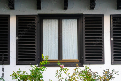 Gray shutters on the window on a white wall. Vintage buidling with shutters
