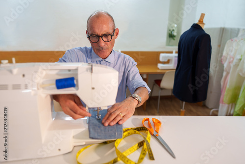 Mature tailor working on a sewing machine, creating a custom garment with precision and craftsmanship