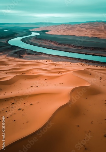 Winding turquoise river flowing through vast orange sand dunes