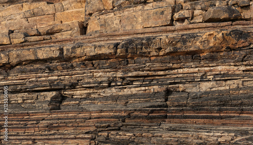 Rugged cliff face showcasing diverse sedimentary rock layers and geological stratification with sedimentary formation background landscape geological mountain material structure