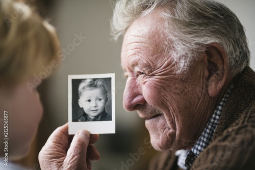 Grandfather showing grandchild a vintage childhood photo indoors