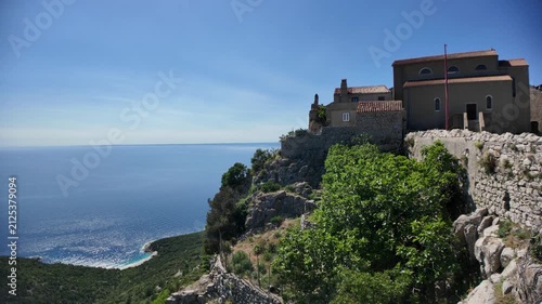 Lubenice medieval village buildings high on a cliff offering panoramic views of Adriatic Sea and Sveti Ivan beach below, representing ancient heritage and Croatian tourism of Cres Island in Croatia
